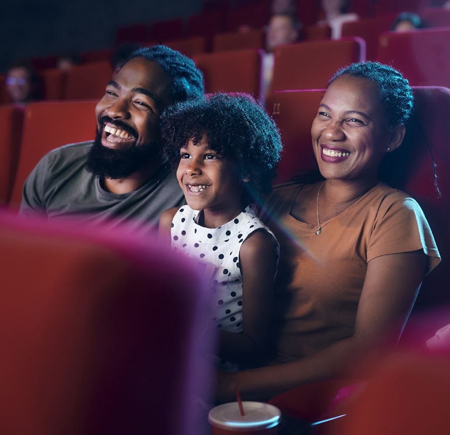 Família sorrindo enquanto assiste a uma sessão de cinema